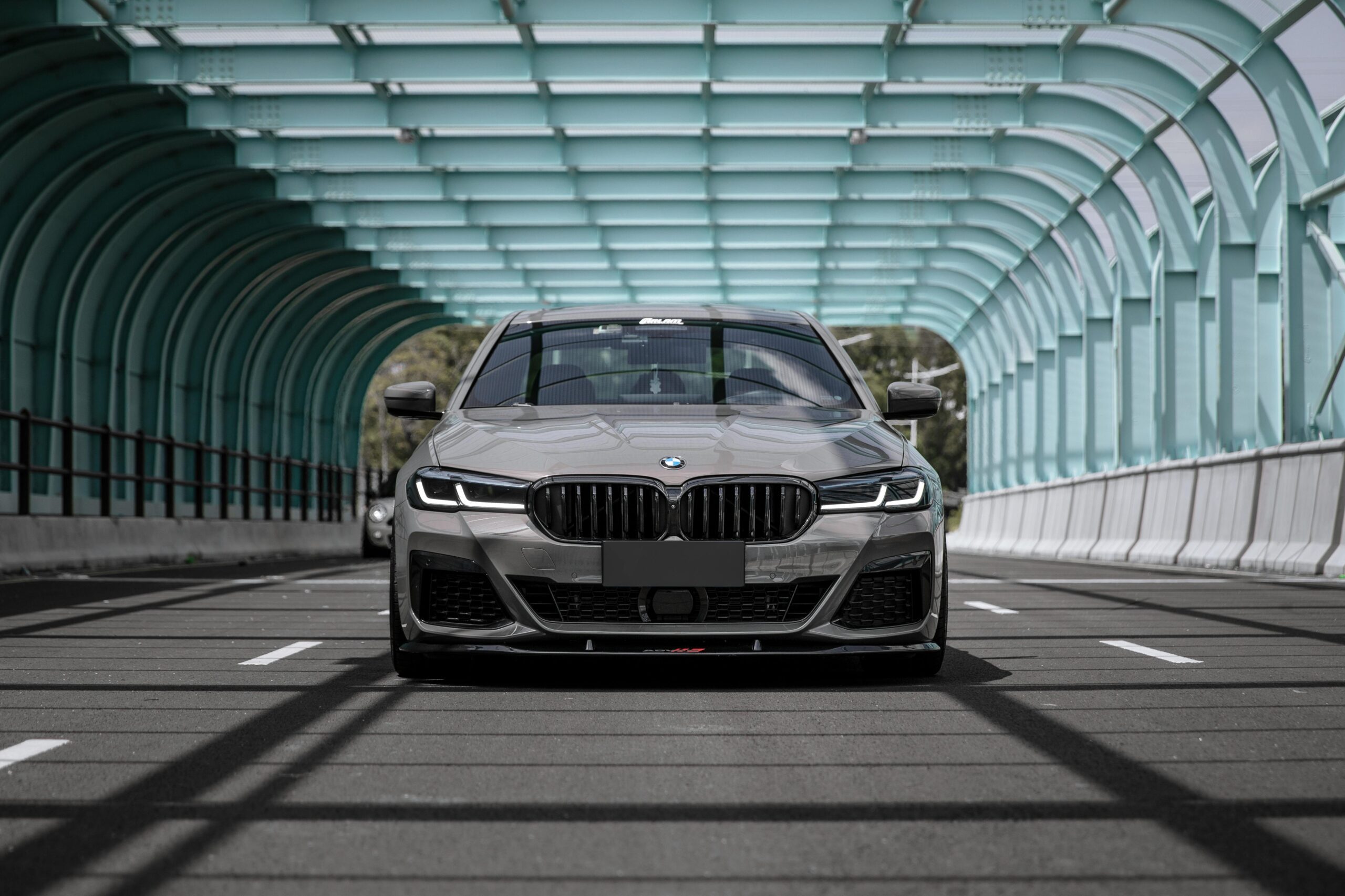 Front view of a luxury BMW 5 Series car parked in a modern tunnel, showcasing design and elegance.